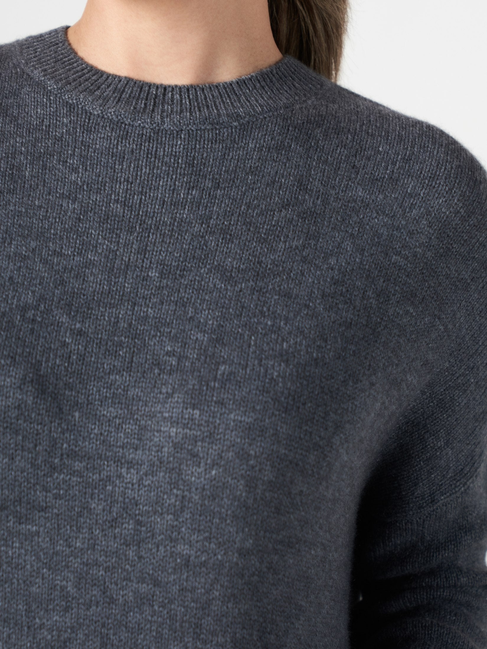 Close-up of a charcoal grey cashmere dress with a round neck and relaxed fit knit fabric texture.
