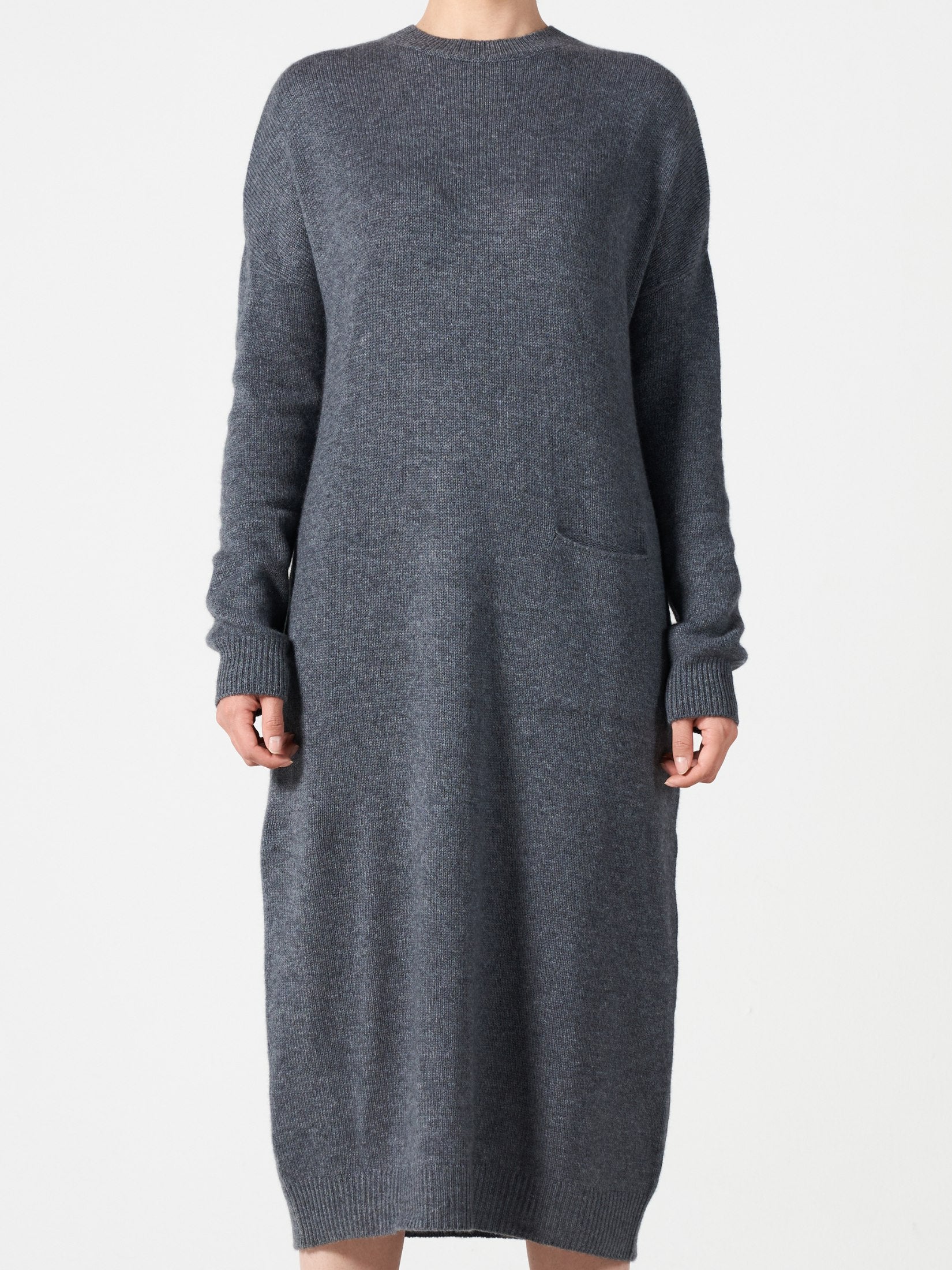 Woman wearing a relaxed fit grey cashmere dress with one pocket and round neck, mid-length from shoulder to hem