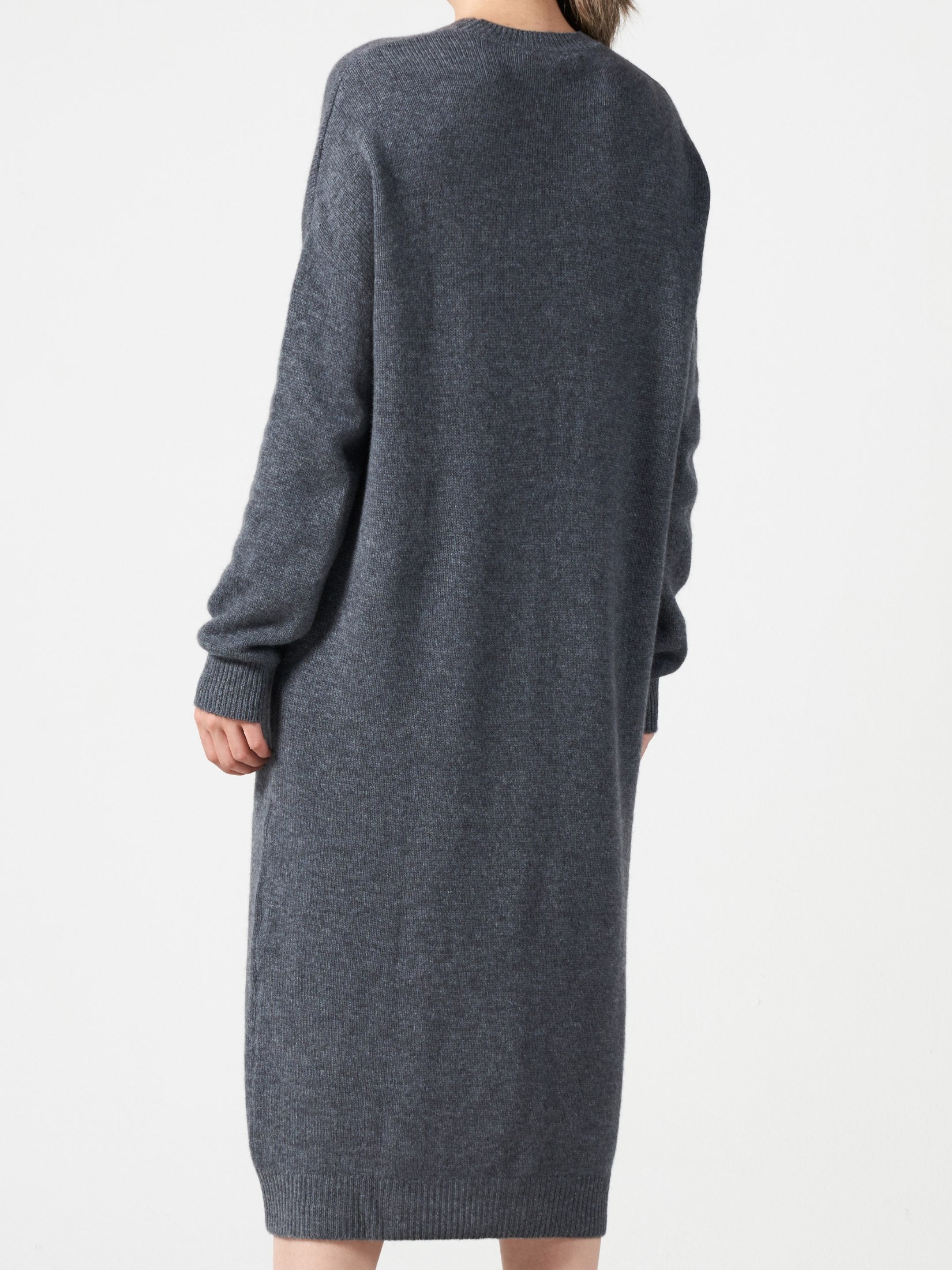 Back view of a woman wearing a grey loose fit cashmere dress with one pocket and long sleeves