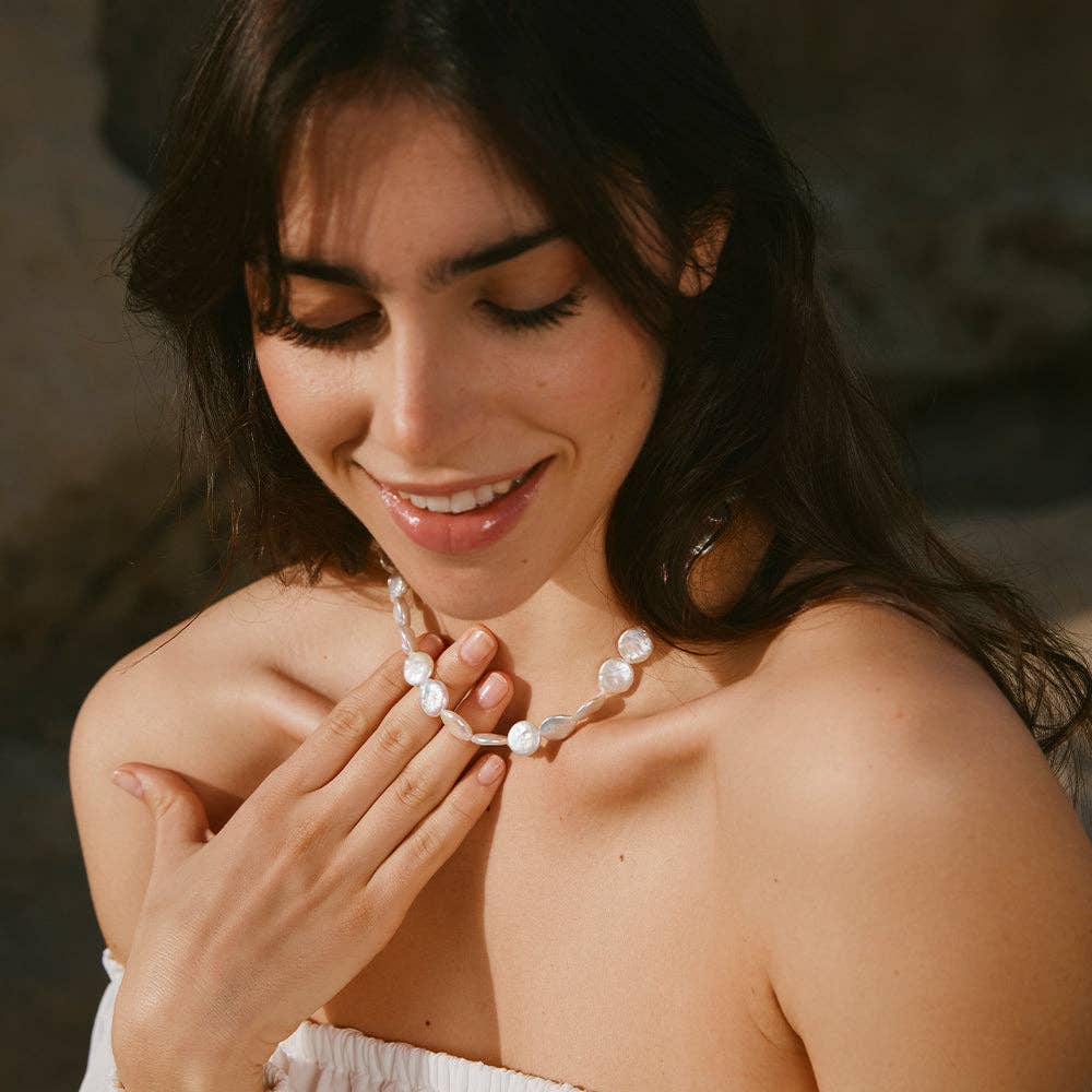 Model wearing a coin-shaped pearl necklace, adding an elegant touch to the look.
