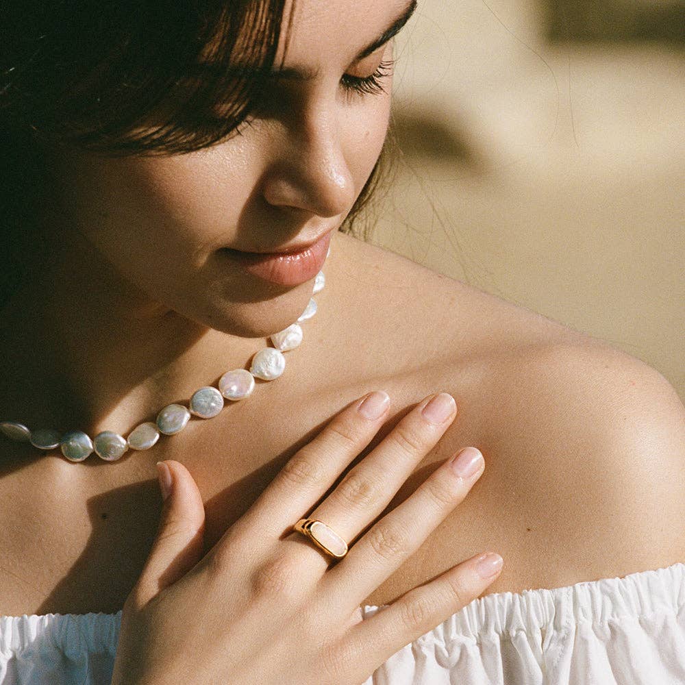 Model wearing a coin-shaped pearl necklace, adding an elegant touch to the look.