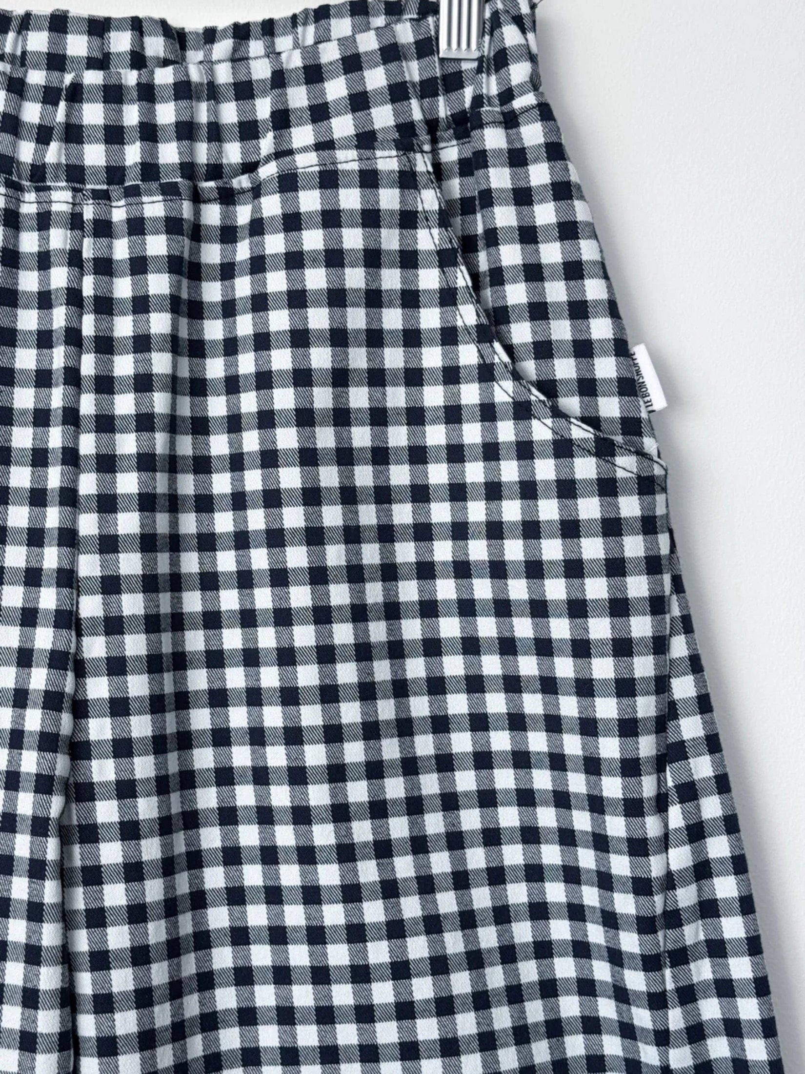Pocket detail of  navy gingham arc pants, showcasing their structured design.