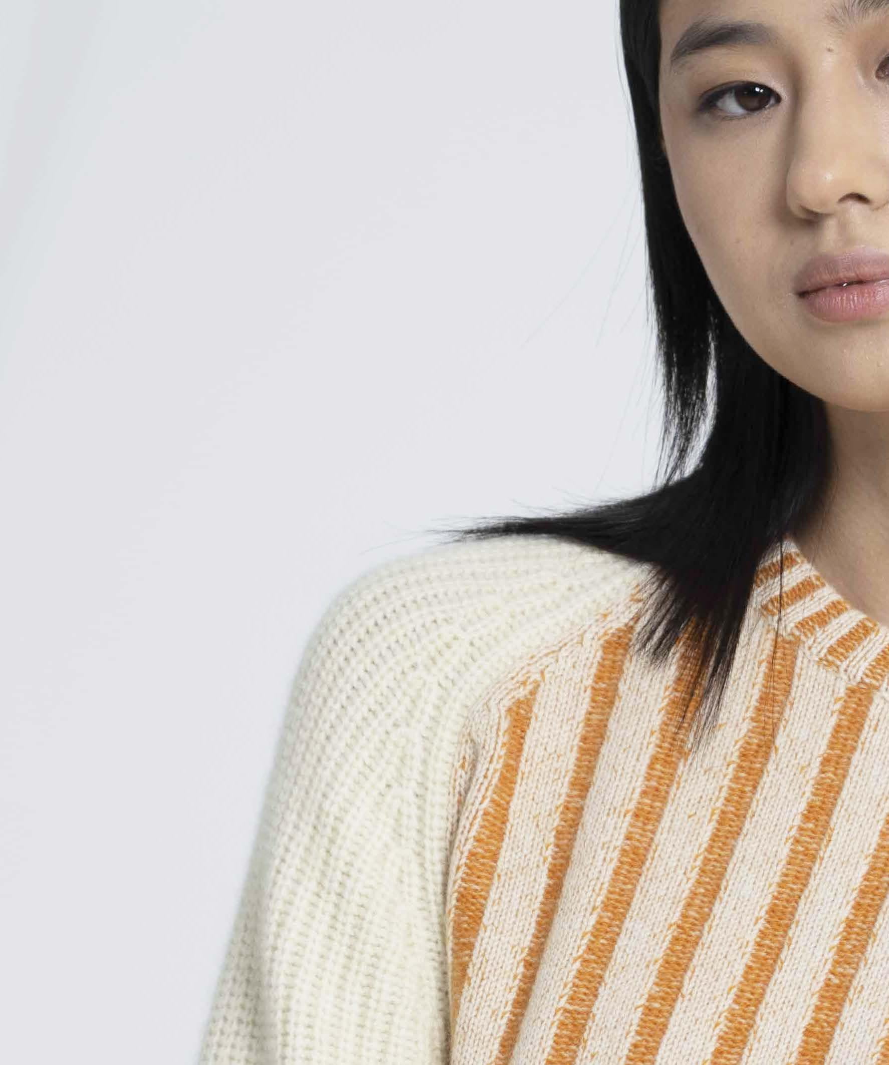 Model wearing orange striped cashmere sweater, showcasing a cozy fit with bold stripes and a soft, luxurious texture.